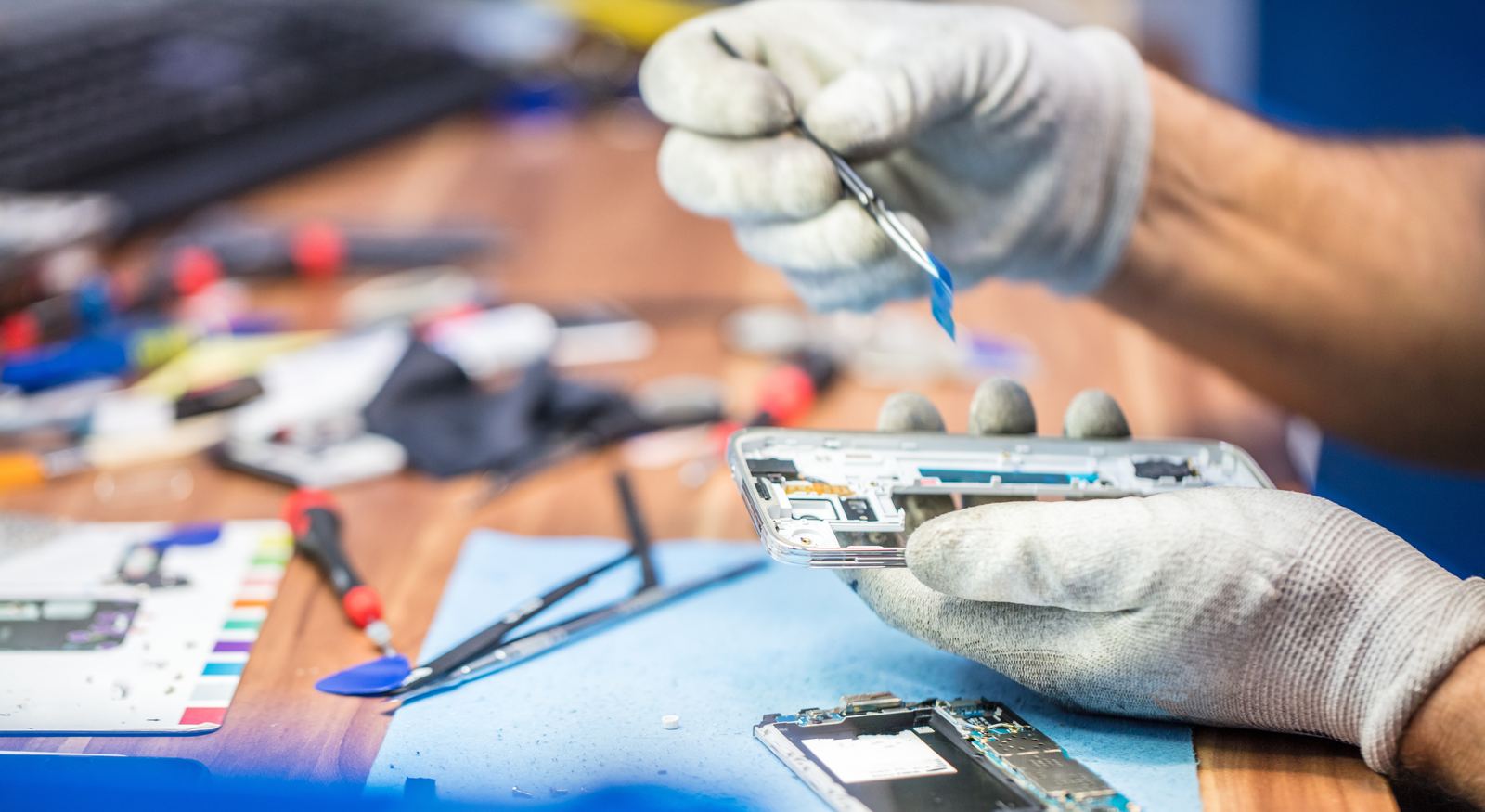 Technician using tweezers on a phone circuit board